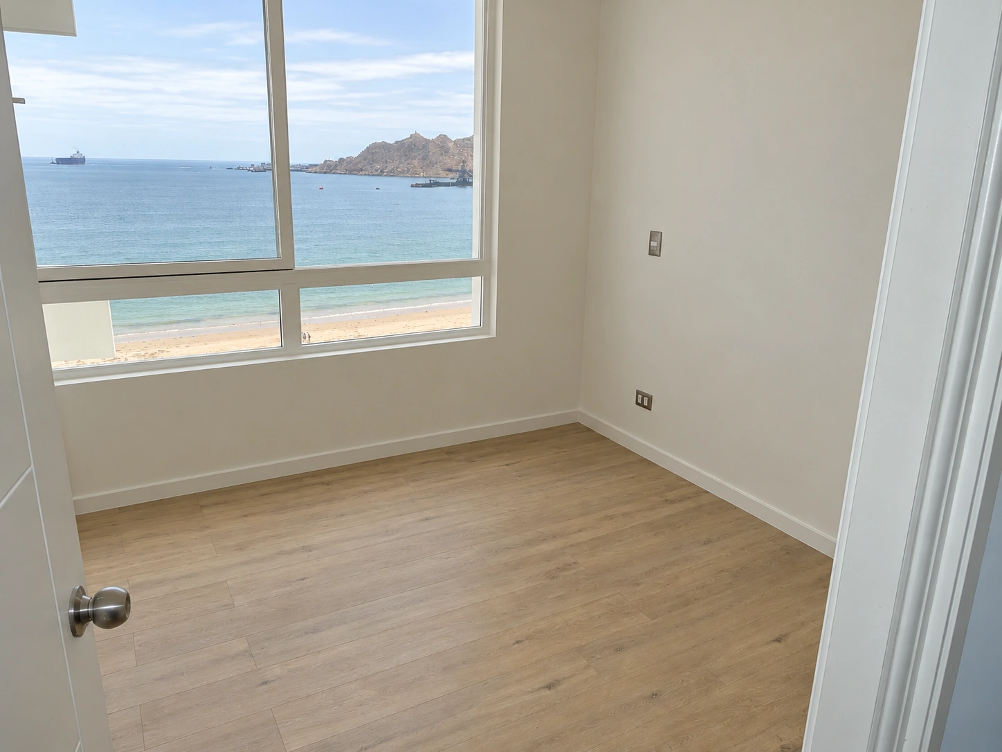 Dormitorio con piso de terminación tipo madera y vista al mar