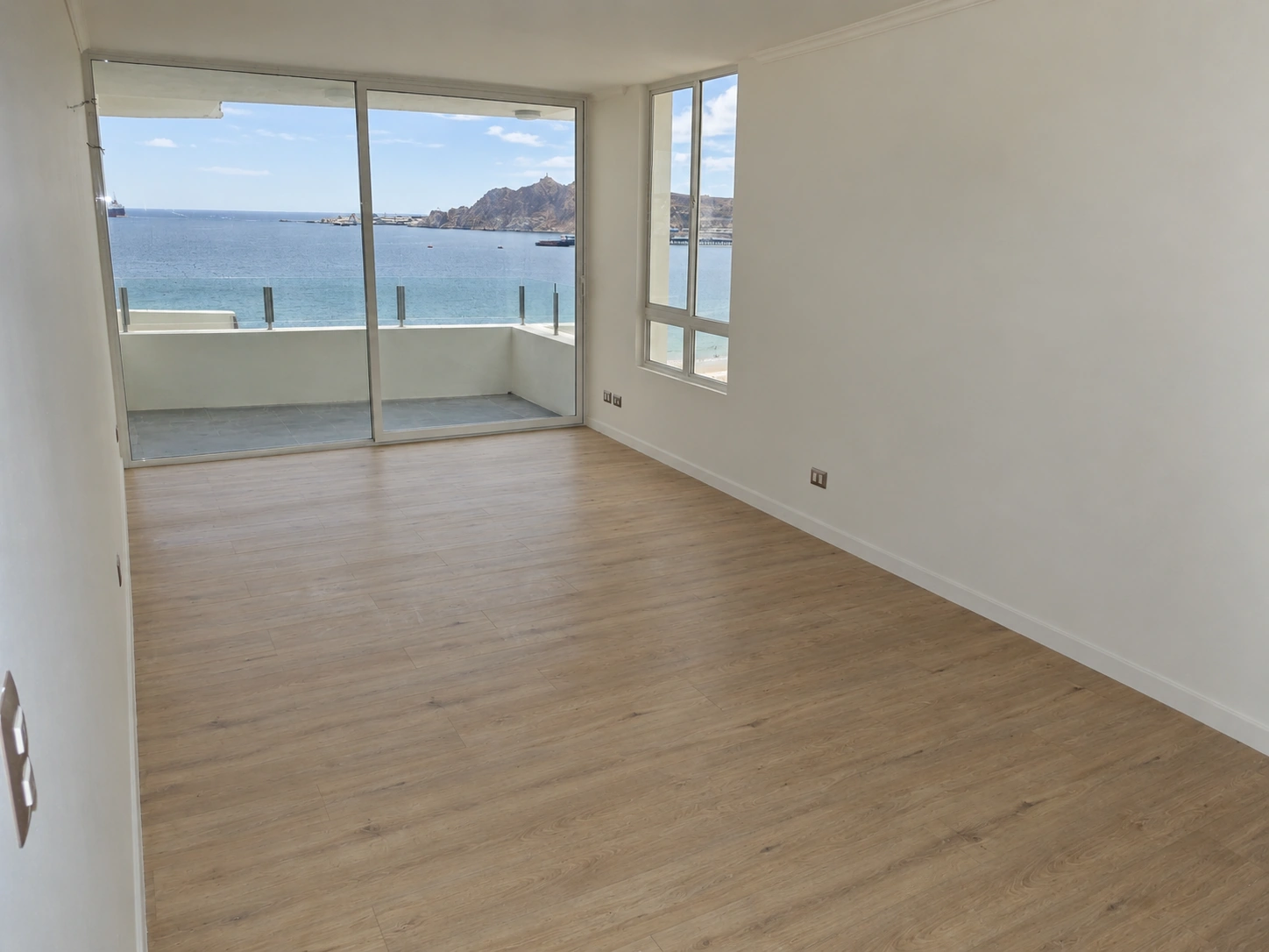 Living amplio con piso de terminación tipo madera y vista al mar